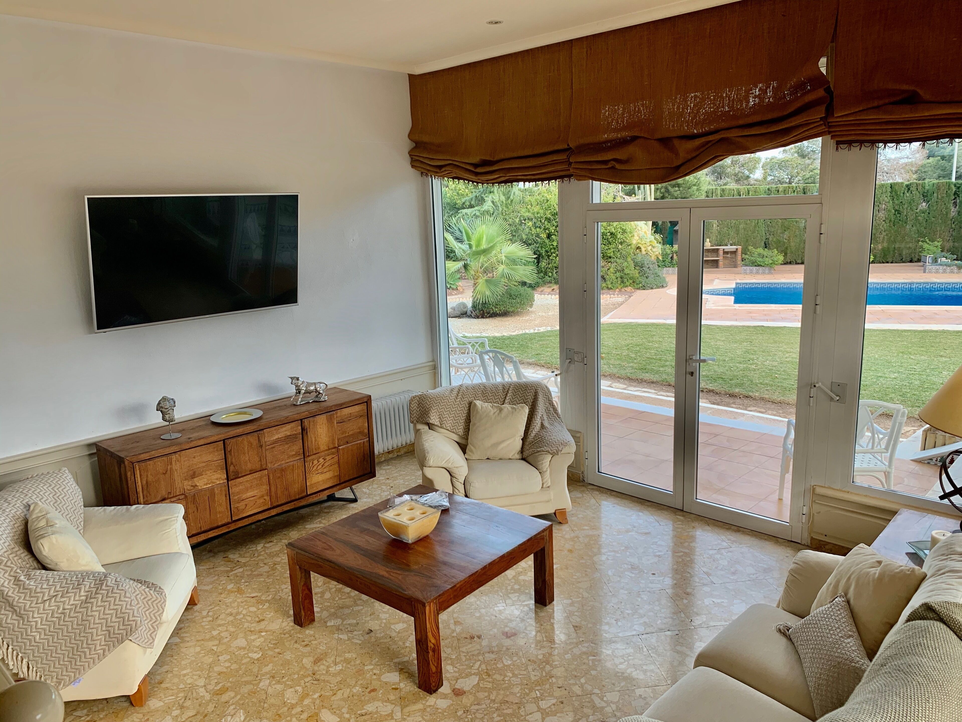 Una sala de estar con un televisor grande, un mueble de madera y una mesa de centro.