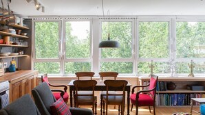 Una sala de estar acogedora con chimenea, muebles de madera y un ventanal con vistas a árboles.