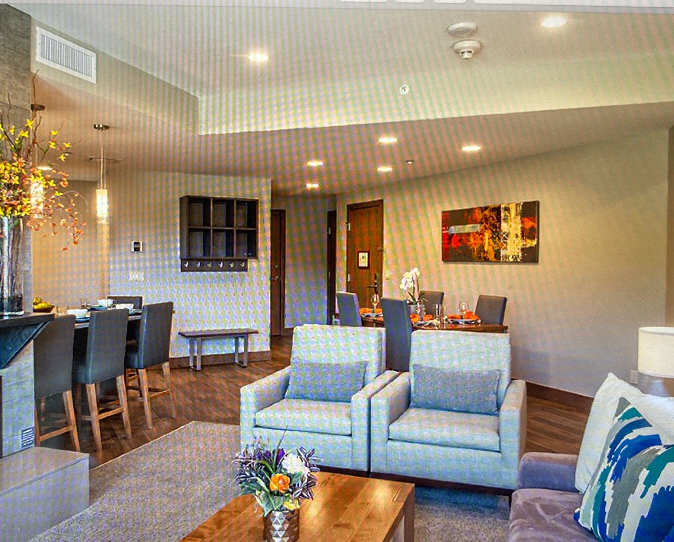 A modern living room with a dining area, featuring a sofa set, a coffee table, and a dining table with chairs.