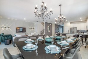 A modern dining area with a long table set for a meal, surrounded by comfortable seating.
