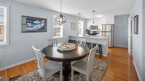 A modern kitchen with white cabinets, a central island, and pendant lighting. - Classic Beach Cottage on Oceanside of Wrightsville Beach-Upper Unit (Wrightsville Beach)