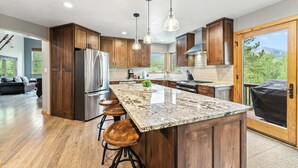 Une cuisine moderne avec des meubles en bois, des appareils en acier inoxydable et un grand îlot central doté de tabourets de bar.