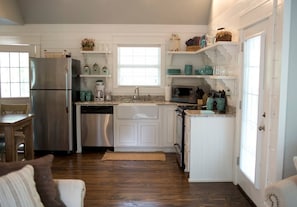 Une cuisine avec des meubles blancs, des appareils en acier inoxydable et des touches de couleur turquoise.
