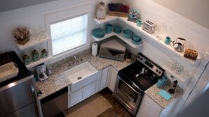 A compact kitchen with white cabinetry, a granite countertop, a stainless steel stove, and a microwave. - Mtn Cabin Lake Hot Tub | Kayak | Fish | AtvTrls (MENA)