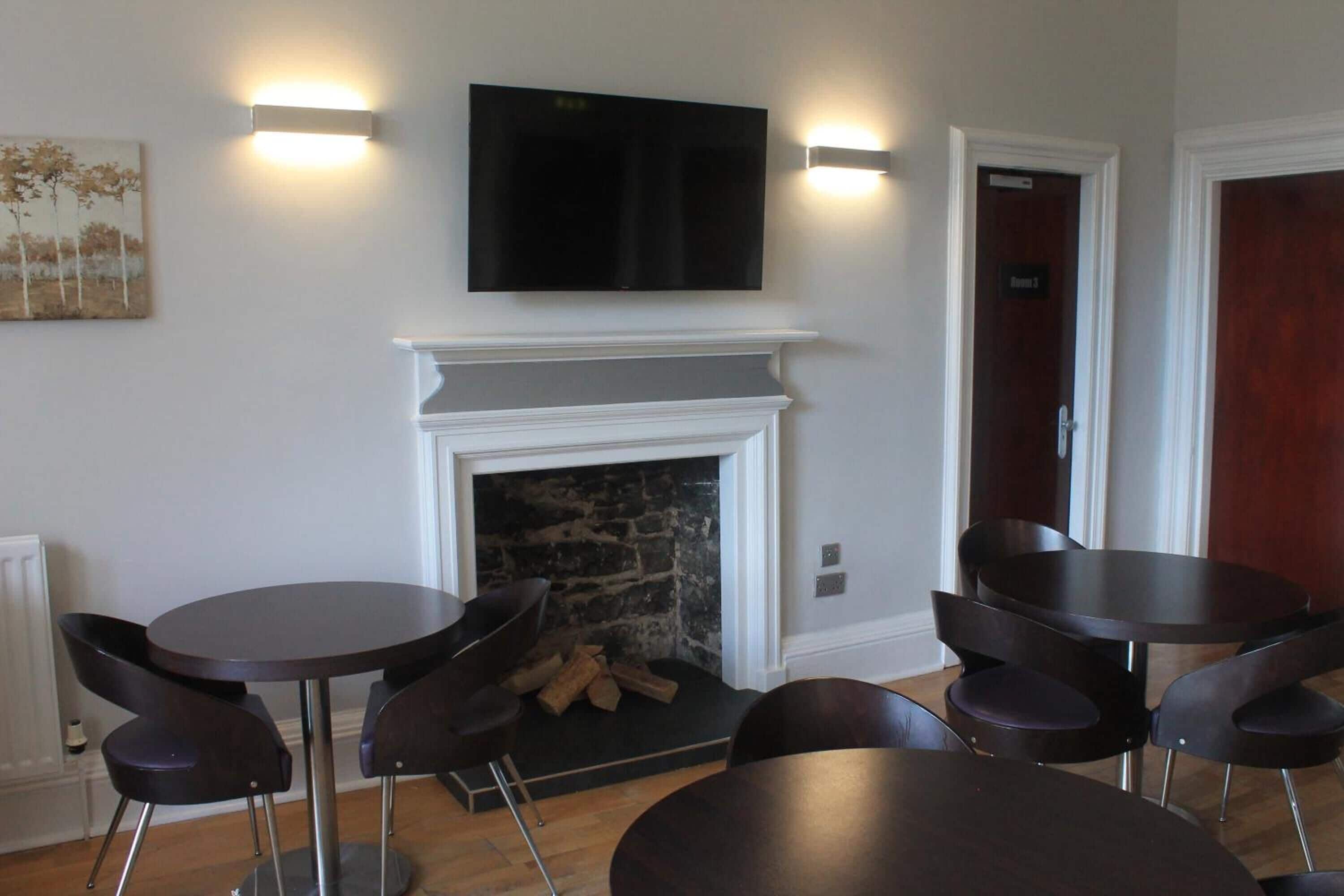 A room with a fireplace, a flat-screen TV mounted above it, and a door labeled "Room 3".