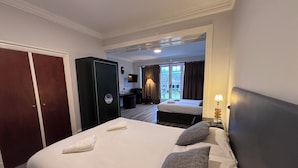Een hotelkamer met een groot bed, een kledingkast, een bureau met stoel en een raam met gordijnen.