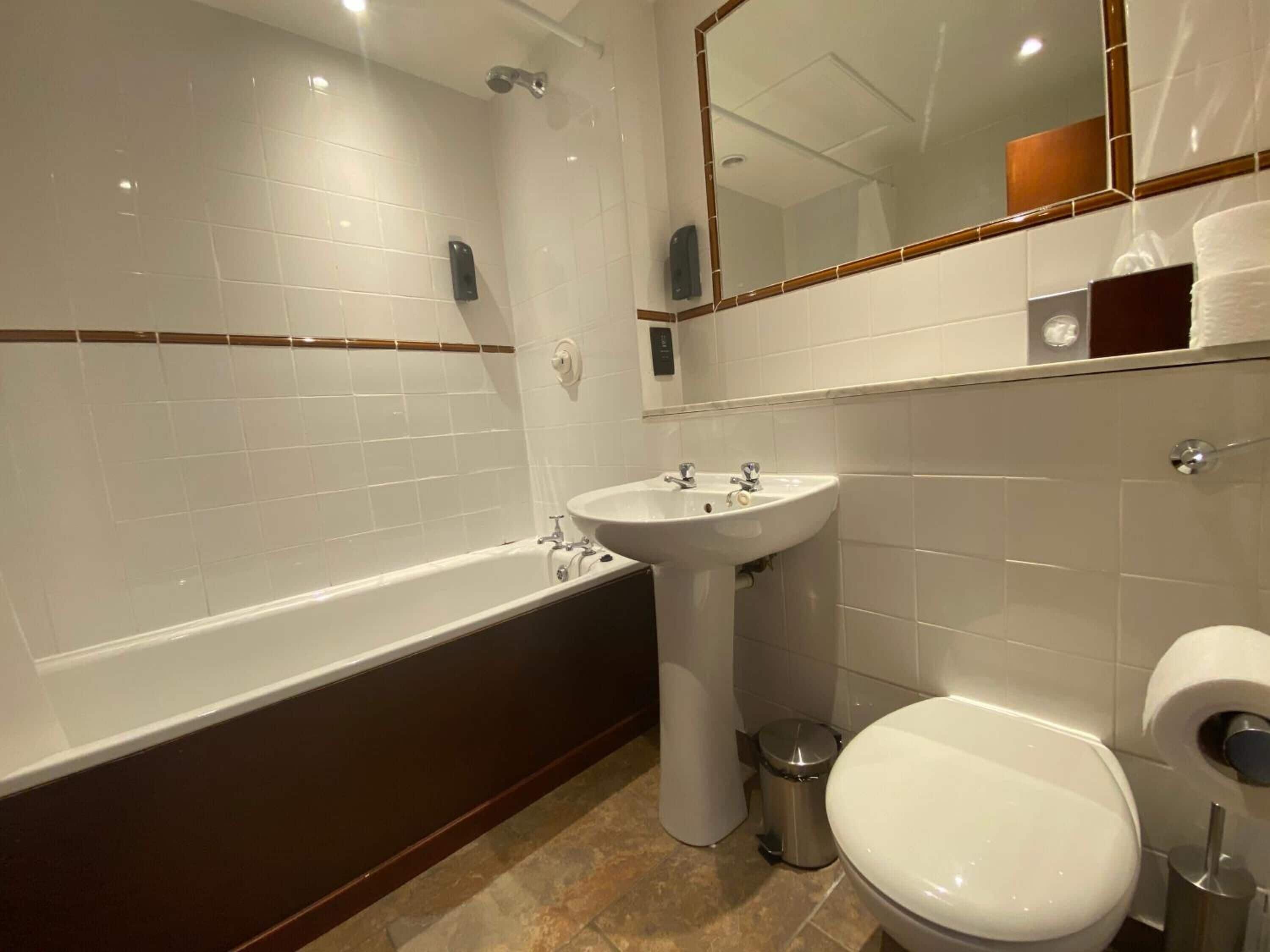 A modern bathroom with a bathtub, sink, toilet, and a mirror.