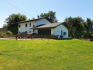 A two-story building with a garage, a fenced driveway, and a grassy lawn.