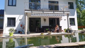 A two-story house with a balcony, a swimming pool, and outdoor furniture. - Ferienwohnung bis 4 Personen, Balkon, 75 qm (Fridolfing)