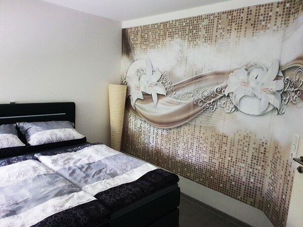 A bedroom with a bed, a decorative wall, and a lamp.