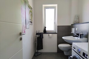 A compact bathroom with a toilet, sink, and a window.