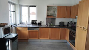 A modern kitchen with wooden cabinets, a built-in oven, a microwave, and a dishwasher. - Ferienwohnung bis 4 Personen, Balkon, 75 qm (Fridolfing)