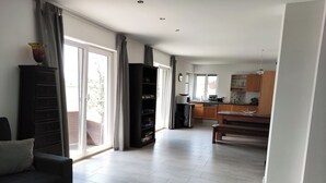 A spacious living area with a sofa, a bookshelf, and a dining table. - Ferienwohnung bis 4 Personen, Balkon, 75 qm (Fridolfing)
