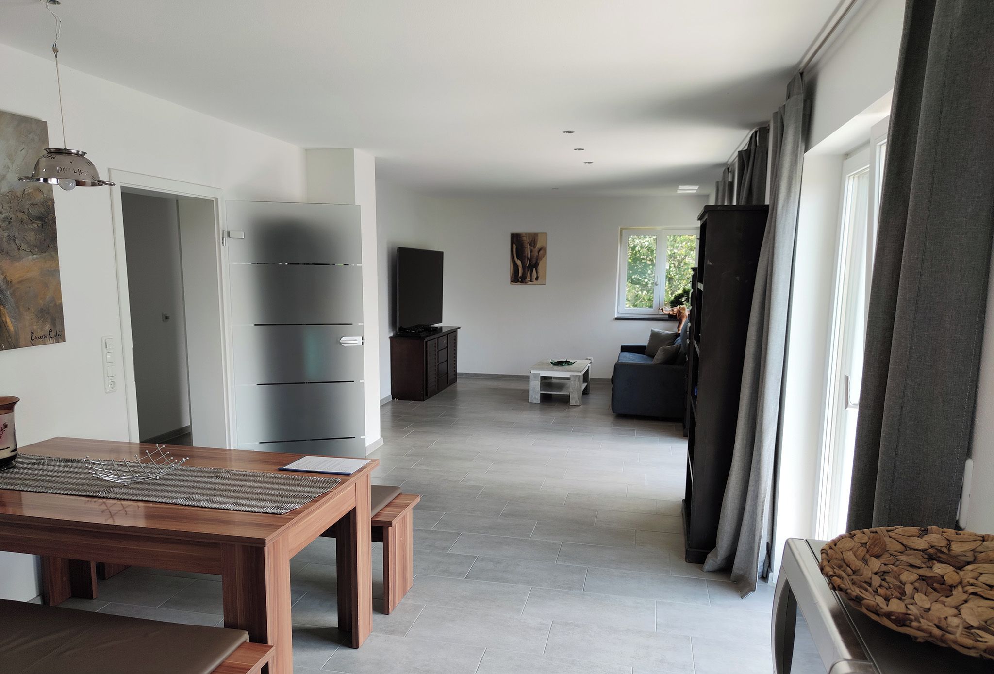 Ein geräumiger Wohnbereich mit einem Holzessttisch, einer Couch und einem Fernseher.