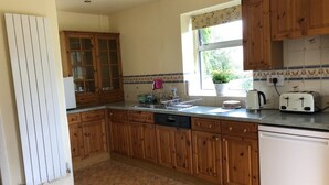Une cuisine avec des meubles en bois, un lave-vaisselle, une fenêtre avec vue et un pare-feu en carrelage.
