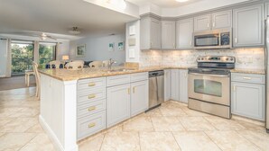 Una cocina amplia con encimeras de granito, electrodomésticos de acero inoxidable y armarios color gris claro.