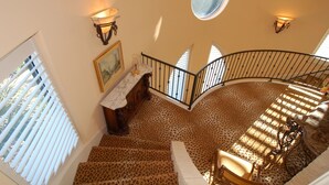 A spiral staircase with a leopard print carpet, a round window, and wall sconces. - Hidden apartment at Villa del Sol ~ Amazing Sunsets -Spacious Luxury (Austin)