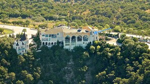 A large, historic mansion with multiple arches and a prominent tower, surrounded by dense forest and a winding road. - Hidden apartment at Villa del Sol ~ Amazing Sunsets -Spacious Luxury (Austin)