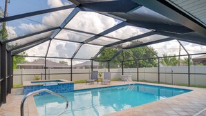 A covered swimming pool with a clear view of the sky, a small hot tub, and two lounge chairs. - 3 Bedroom, Huge Pool, Hot Tub, Screened in Lanai in the coveted 500 block (Naples)
