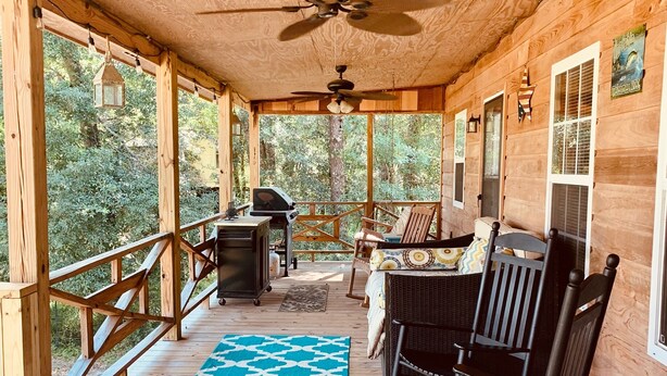 A wooden deck with a ceiling fan, a grill, and outdoor seating. - The Leaf River Yacht Club (Petal)