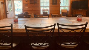 A wooden interior with a dining table, chairs, a ceiling fan, and a TV. - The Leaf River Yacht Club (Petal)