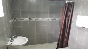 Een badkamer met een wastafel, douche en toilet.
