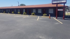 Een motel met een rood dak en een bord waarop 'Sunny South Motel' en 'Schoon Comfortabel' staat.