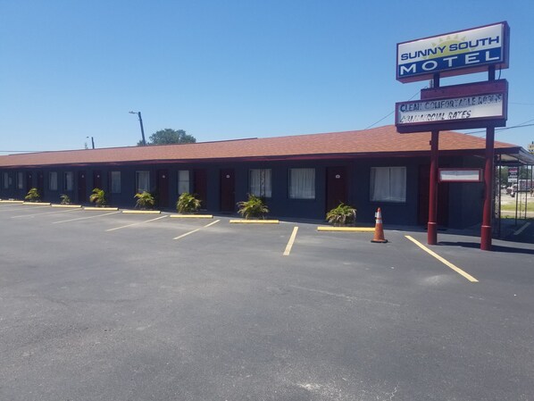 A motel with a red roof and a signboard advertising "Sunny South Motel" and "Clean Comfortable Rooms." - Sunny South Motel (Tampa)