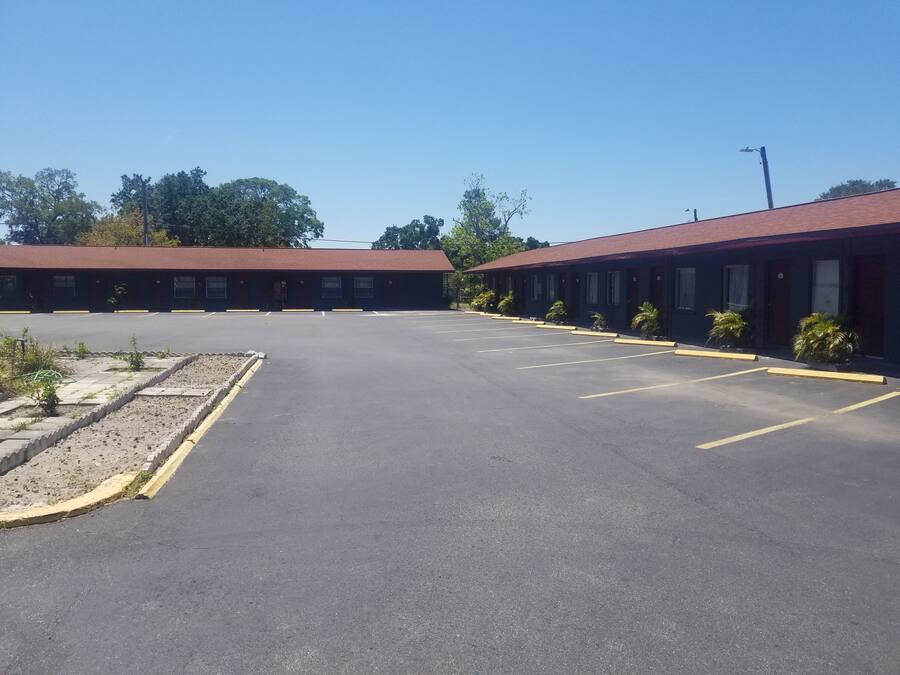 A parking lot with a row of motel-style buildings.