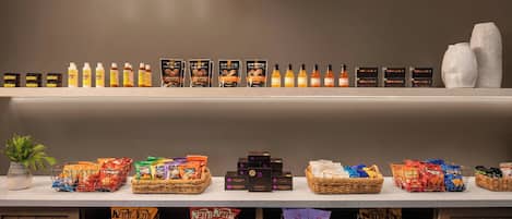 A well-organized store with shelves of snacks, bottles, and baskets of goods.