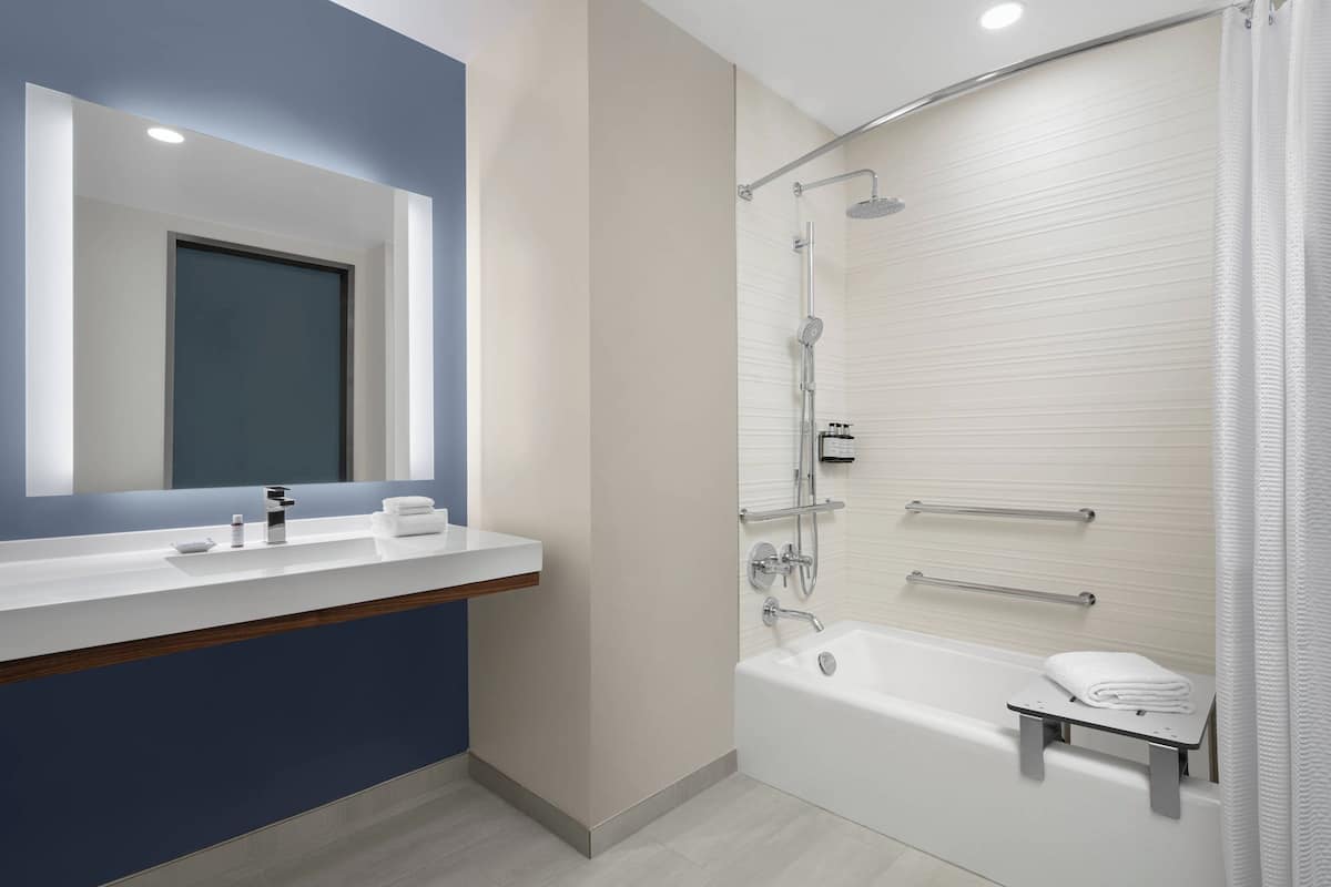 Un baño moderno con un espejo grande, una bañera y zona de ducha.