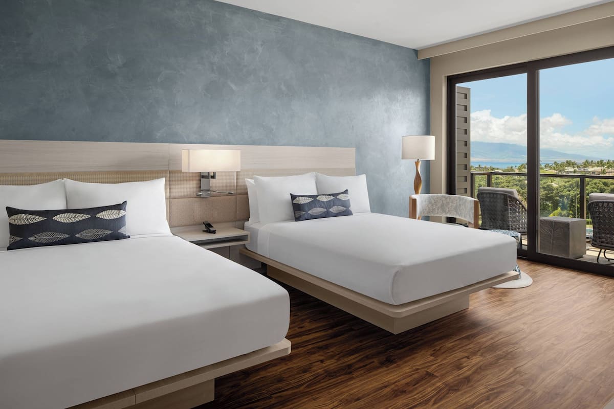 Habitación de hotel con dos camas, un ventanal con vistas y un balcón con sillas.