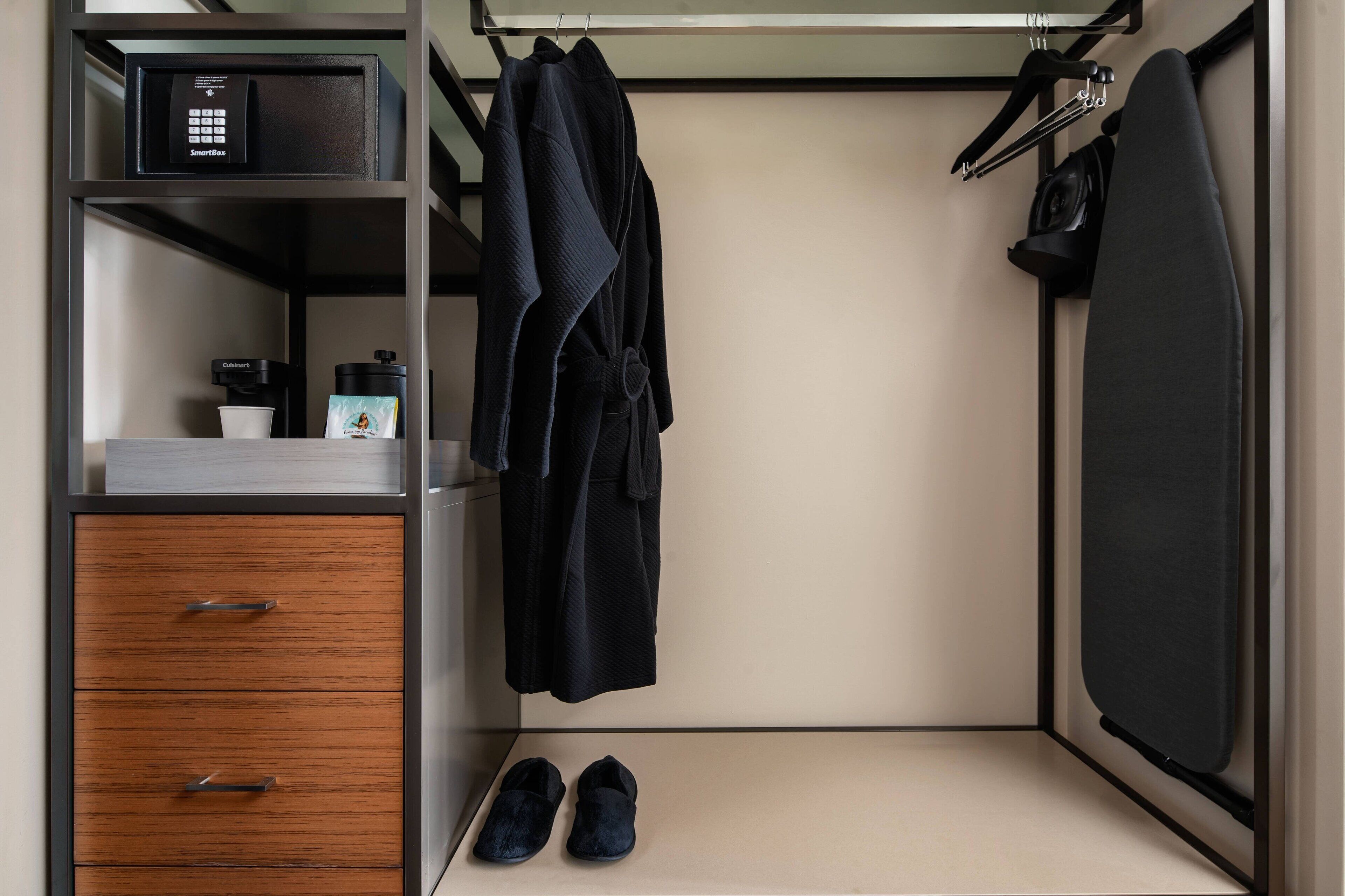 A compact room with a wardrobe, a coffee maker, and a pair of shoes.