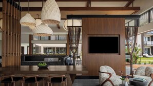 Un espacio moderno para relajarse con barra de madera, asientos y un televisor grande.