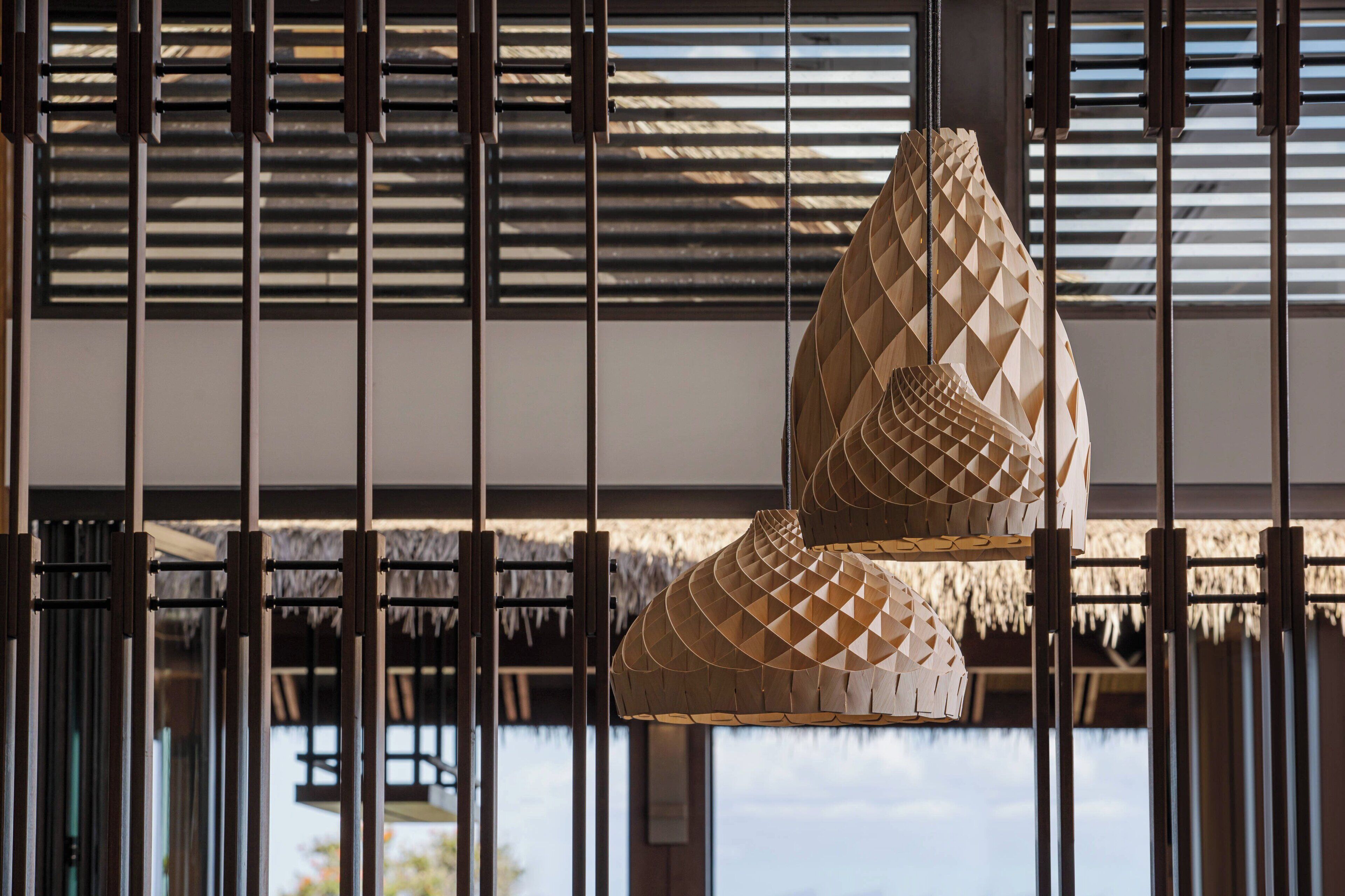 Une pièce dotée d’un toit de chaume et d’un luminaire suspendu en bois.