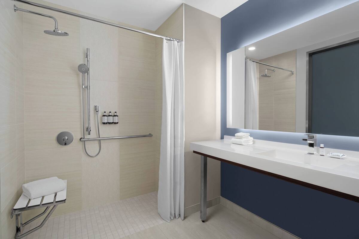 Un baño moderno con ducha, lavamanos y espejo.
