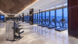 A modern gym with treadmills aligned against a large window overlooking a cityscape. - Hyatt Regency Lanzhou (Lanzhou)