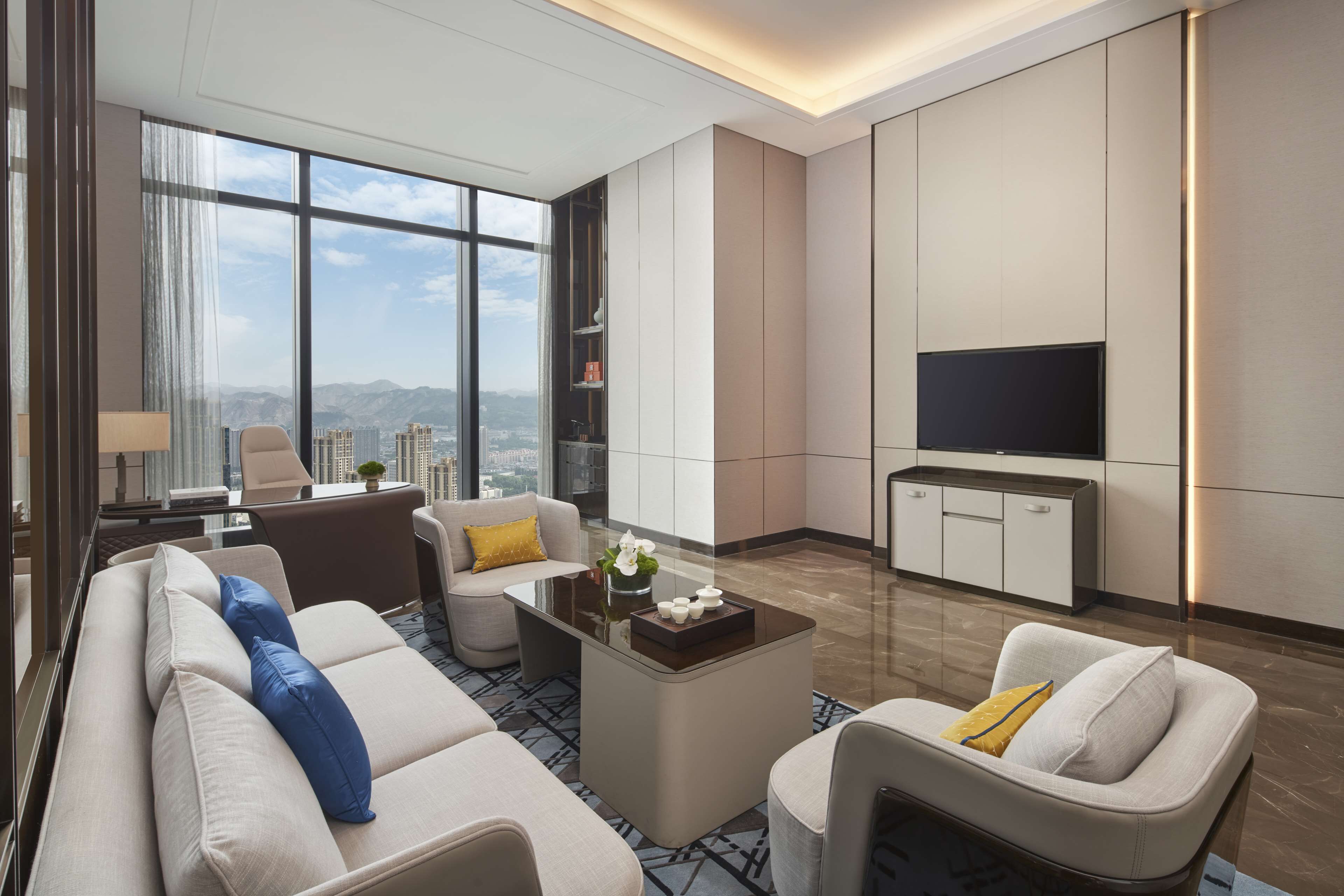 Una sala de estar moderna con un sofá, sillones, una mesa de centro y un televisor de pantalla plana.