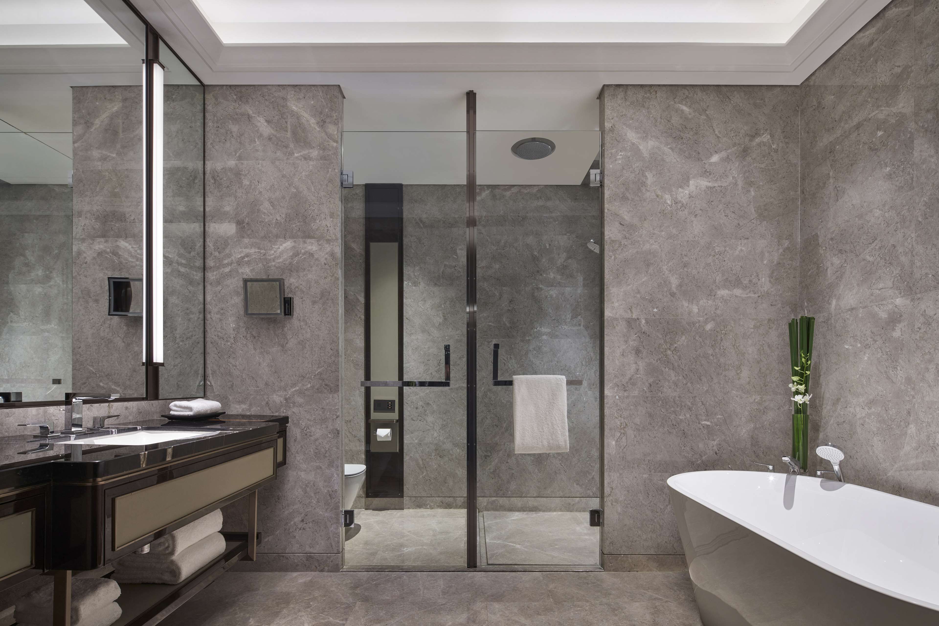 A modern bathroom with a glass-enclosed shower, a freestanding bathtub, and a vanity with a mirror and sink.