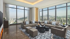 A spacious living room with a large sofa set, a coffee table, and a TV. The room has large windows offering a city view. - Hyatt Regency Lanzhou (Lanzhou)