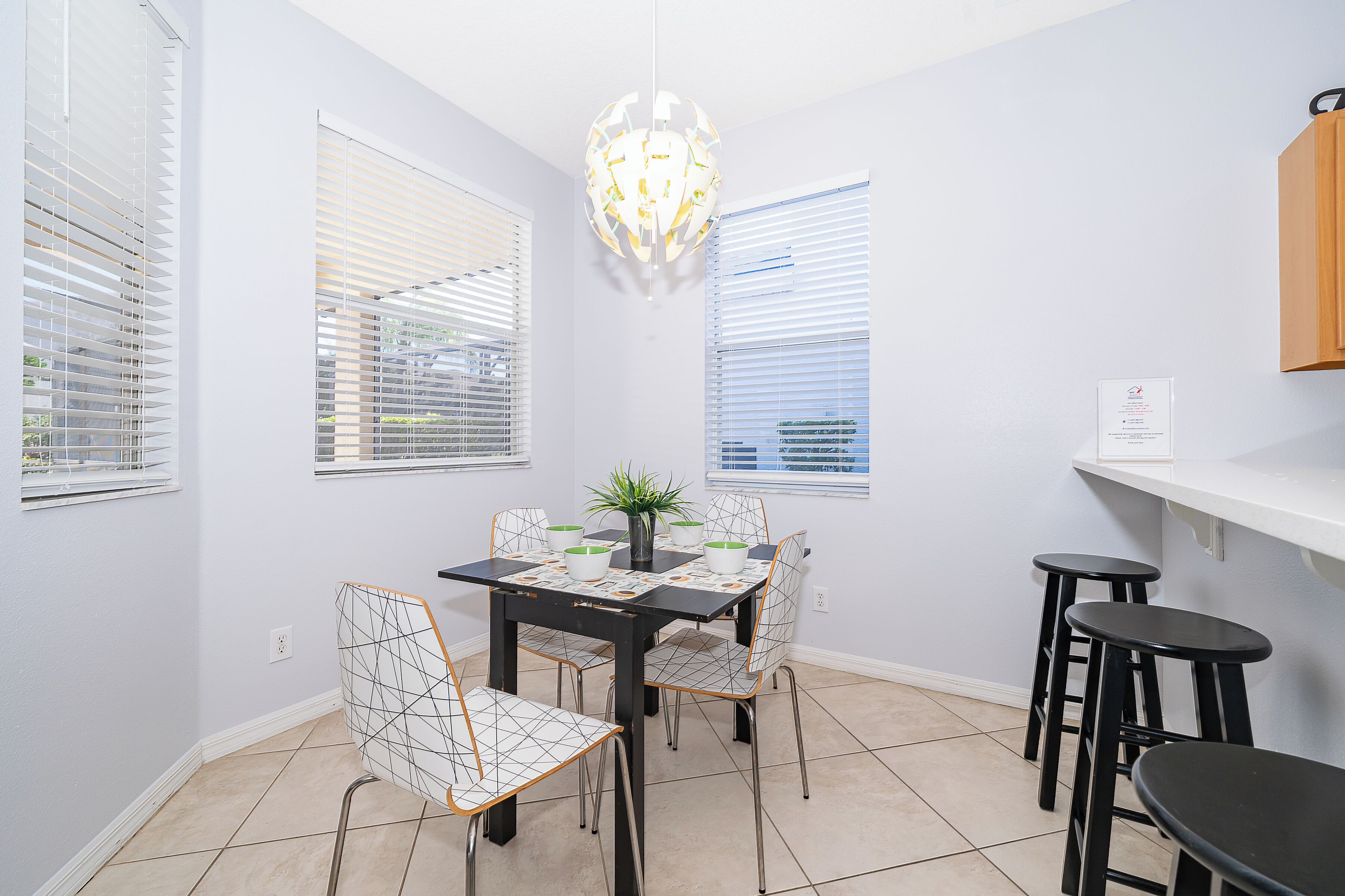 A dining area with a black table, white chairs, and a chandelier.