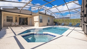 A covered outdoor swimming pool with lounge chairs and a patio area.