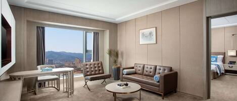 Una habitación de hotel moderna con un ventanal grande, un sofá, una mesa de centro y un televisor.