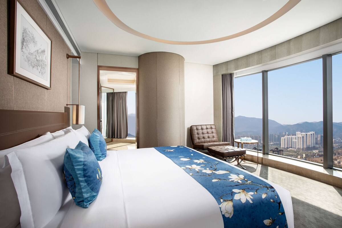 A modern hotel room with a large bed, a view of the city, and a balcony.