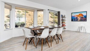A dining area with a large table, white chairs, and a ceiling fan.
