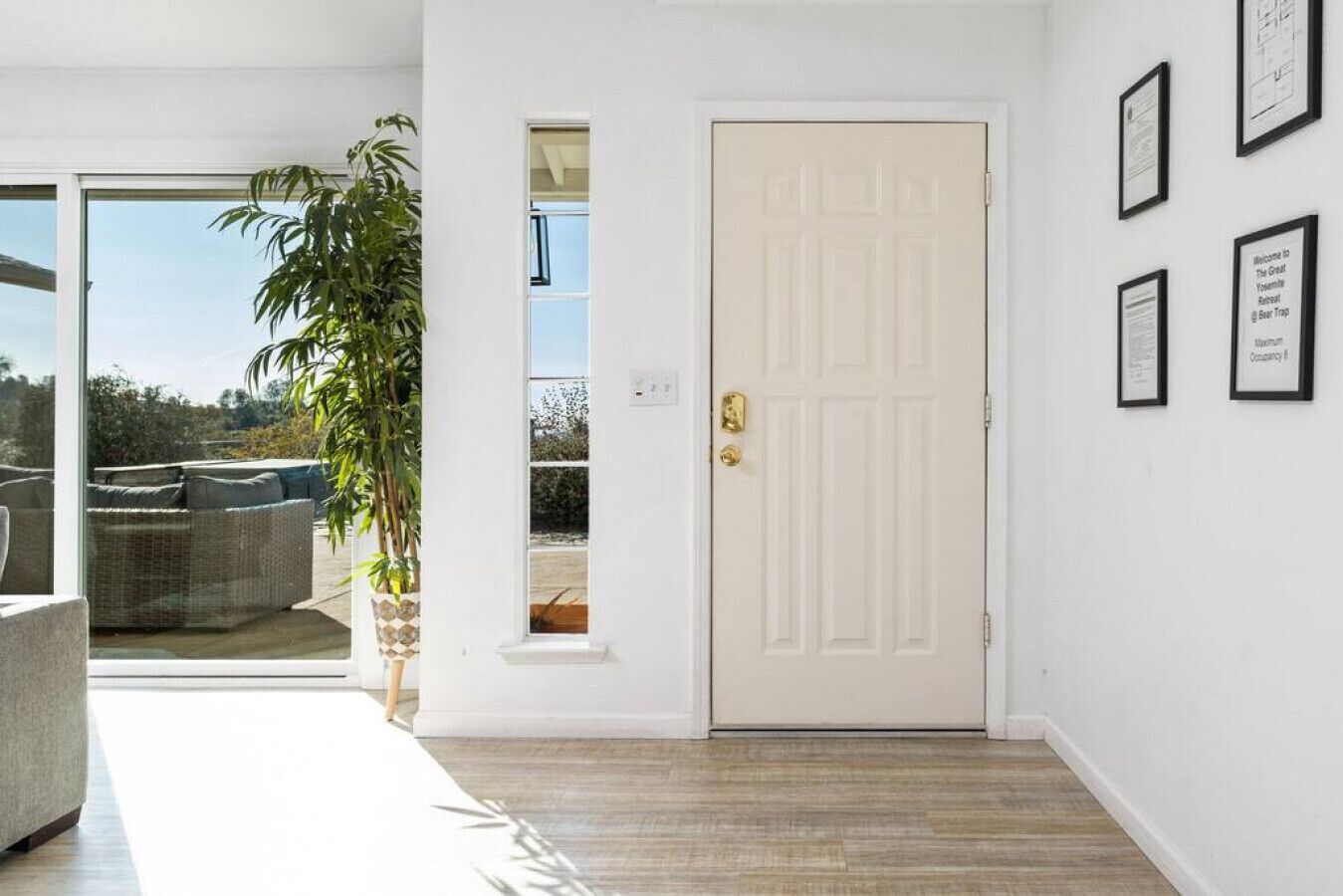 A white door with a brass handle, a potted plant, and framed certificates on the wall.