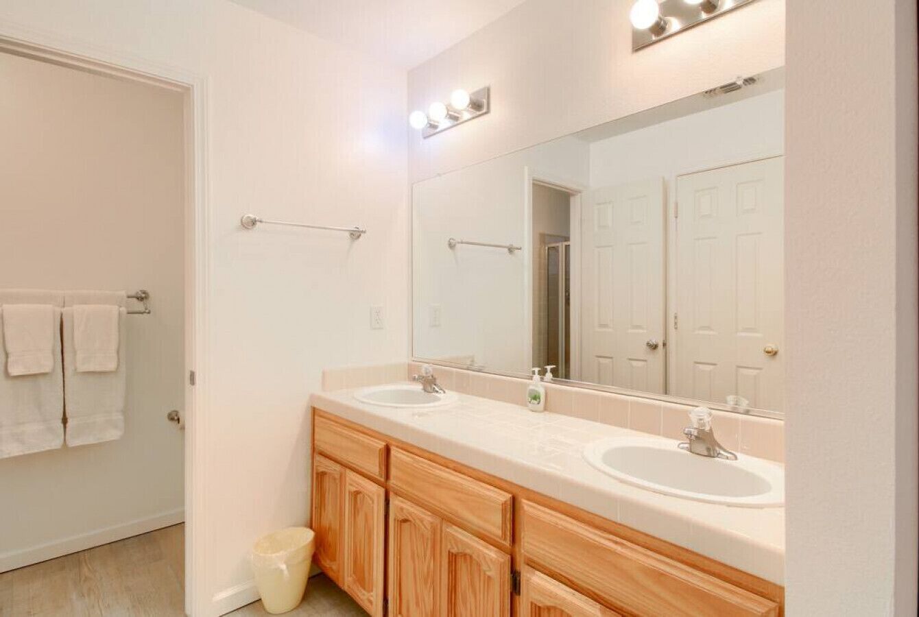 A bathroom with two sinks, wooden cabinets, a large mirror, and a towel rack.