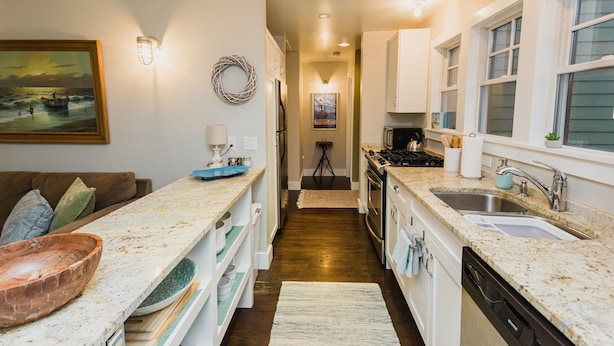 A kitchen with white cabinets, granite countertops, a stove, and a sink.