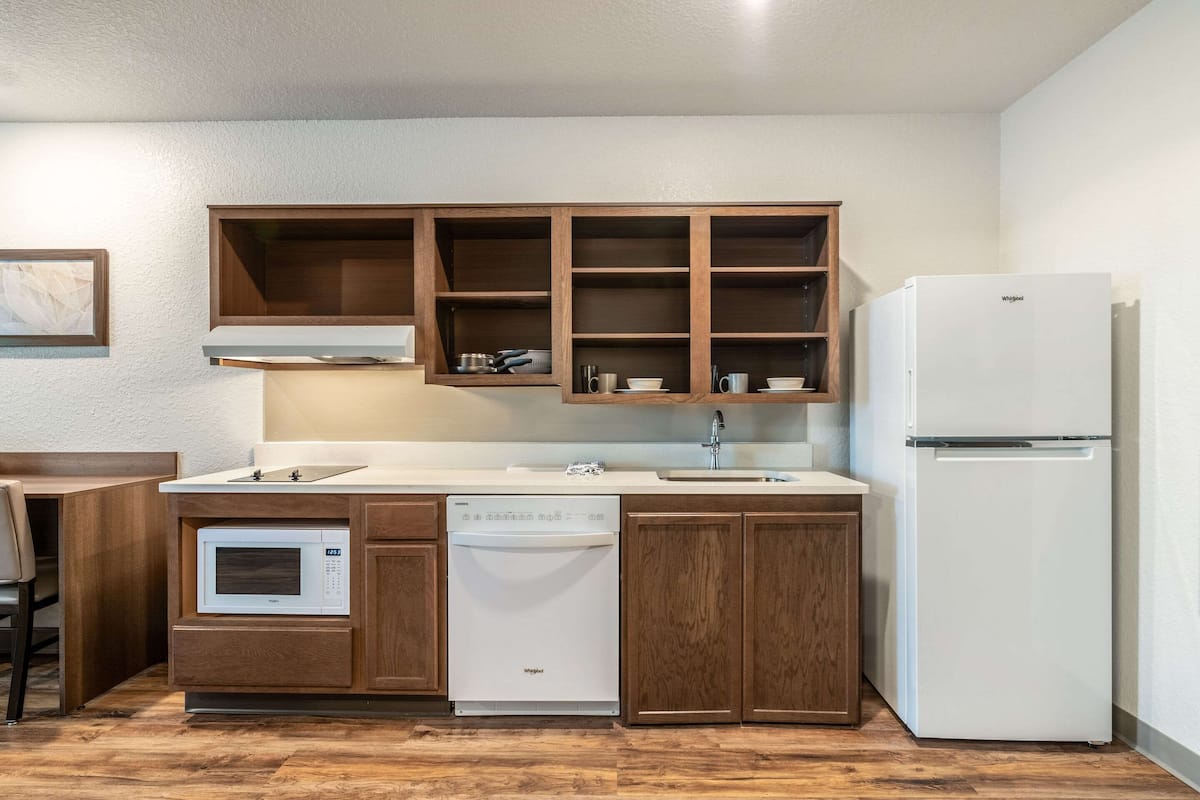A compact kitchen with wooden cabinets, a built-in microwave, dishwasher, and a refrigerator.