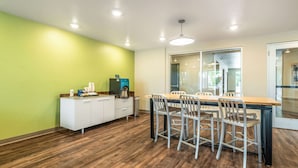 A modern kitchen with a wooden table and chairs, a white cabinet, and a coffee machine. - WoodSpring Suites Sanford North I-4 Orlando Area (Sanford)
